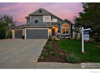 Charming two-story home featuring a well-manicured lawn, lovely landscaping, and a three car garage at 810 Trail Ridge Dr, Louisville, CO 80027