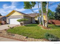 Charming yellow home with well-manicured lawn and mature birch trees in the front yard at 1030 S Fulton Ave, Fort Lupton, CO 80621