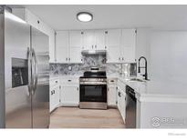 Modern kitchen featuring stainless steel appliances, white cabinetry, and stylish backsplash and countertops at 12525 E Tennessee Cir # E, Aurora, CO 80012