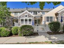 Charming townhome featuring stone accents, a white picket fence, and well-manicured landscaping at 14246 Pikeminnow Pl, Broomfield, CO 80023