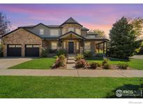 Charming home features a stone and stucco facade, well-manicured lawn, and inviting covered porch at 1702 Montgomery Cir, Longmont, CO 80504
