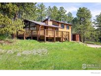 Charming exterior view of a brown home, surrounded by towering trees, complemented by a spacious wrap-around deck at 201 Wild Tiger Rd, Boulder, CO 80302