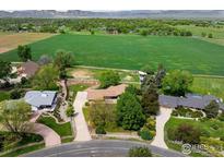 Stunning aerial view of a home with a large green field and mountain views in the background at 2117 Stonehenge Cir, Lafayette, CO 80026