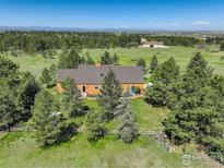 An aerial view shows a charming orange home surrounded by lush greenery and mature trees on a sunny day at 2219 Meadow Green Cir, Franktown, CO 80116