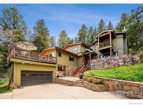 Multi-level home featuring a stone wall, multiple decks, and an attached two car garage at 25808 Sunrise Ln, Golden, CO 80401
