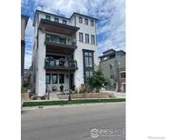 Stylish three-story townhome features a white brick facade, balconies, and a well-manicured front yard at 410 Superior Dr, Superior, CO 80027