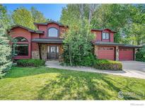 Inviting two-story home with stone accents, lush lawn, and mature trees at 7528 Estate Cir, Niwot, CO 80503