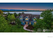 Stunning blue home boasts waterfront views and lush landscaping at dusk at 10481 Oxford Rd, Longmont, CO 80504
