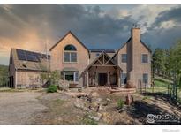 Inviting two-story home featuring a textured facade, solar panels, a stone chimney and decorative wooden accents at 1057 Reed Ranch Rd, Boulder, CO 80302