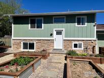Charming two-story home with stone accents, a well-manicured lawn, and a lovely garden out front at 1085 Malory St, Lafayette, CO 80026