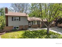 Charming two-story home featuring a well-manicured lawn, brick accents, and mature trees at 1250 Acropolis Dr, Lafayette, CO 80026