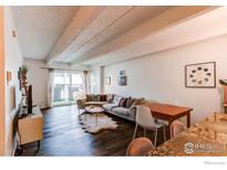 Bright living room featuring exposed beam ceiling, hardwood floors, and access to a patio at 1265 Race St # 408, Denver, CO 80206
