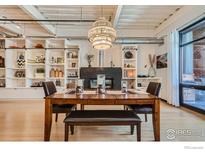 Bright dining room boasts built-in shelving, hardwood floors, and modern chandelier above the wooden dining table at 1360 Walnut St # 202, Boulder, CO 80302
