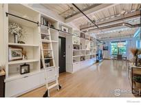 Bright living room features custom built-in shelving with rolling ladder and abundant storage, wood flooring, and modern lighting at 1360 Walnut St # 202, Boulder, CO 80302