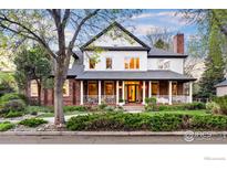 Charming two-story home with brick and white siding, black shutters, a covered porch, and well-manicured landscaping at 2835 Links Dr, Boulder, CO 80301