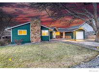 Inviting, green single-Gathering home with a stone chimney, manicured lawn, and driveway with garage at 319 Carter Ln, Longmont, CO 80501