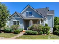 Charming two-story home with blue siding, a covered front porch, and mature landscaping at 4218 San Marco Dr, Longmont, CO 80503