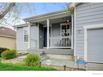 Inviting front porch and entrance to a gray home with well-maintained landscaping at 4312 Windmill Dr, Brighton, CO 80601