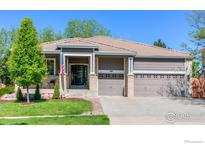 Charming ranch-style home featuring a manicured lawn, three-car garage, and covered front porch at 489 Hayloft Way, Brighton, CO 80601