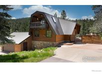 Striking exterior of a wood-sided home with a stone foundation and a standing seam metal roof at 604 Bow Mountain Rd, Boulder, CO 80304