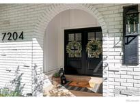 Welcoming arched entryway featuring a black double door adorned with wreaths and a stylish door mat at 7204 Rustic Trl, Boulder, CO 80301