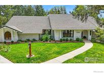Charming brick home with manicured lawn, gray roof, walkway and professionally landscaped front yard at 7204 Rustic Trl, Boulder, CO 80301