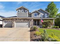Charming gray two-story home with a stone garage and beautifully landscaped front yard at 860 Quintana Ln, Erie, CO 80516