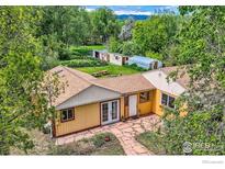 Aerial view of a charming yellow home featuring a beautiful stone walkway, garden, and greenhouse at 1047 Cherryvale Rd, Boulder, CO 80303