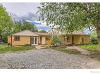 Charming yellow home featuring a gravel driveway, well-manicured lawn, and mature trees, creating a peaceful and inviting atmosphere at 1047 Cherryvale Rd, Boulder, CO 80303