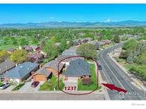 Beautiful aerial view of a single-Gathering home with a large yard, mature trees and mountain views in the background at 1237 Cornell Dr, Longmont, CO 80503