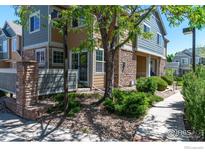 Charming townhome exterior with stone accents, lush landscaping, and inviting walkway at 14300 Waterside Ln # V1, Broomfield, CO 80023