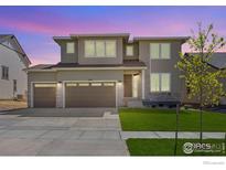 Contemporary two-story home with a three-car garage and stone accents and freshly manicured lawn at 16860 Mckay Dr, Mead, CO 80542