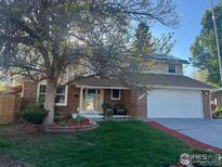 Charming brick home with mature landscaping, cozy front porch, and attached two-car garage at 2229 S Elkhart St, Aurora, CO 80014