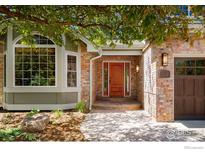 Welcoming front entrance with a beautiful wooden door, brick accents, and manicured landscaping at 2345 Spotswood Pl, Boulder, CO 80304