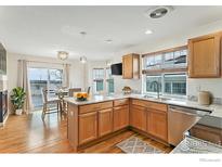 Bright kitchen boasts wood floors, stainless appliances, granite counters and sun-filled dining area at 24285 E Wagontrail Ave, Aurora, CO 80016