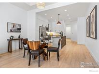Open dining area featuring hardwood floors, a glass table, and modern decor at 3301 Arapahoe Ave # 106, Boulder, CO 80303
