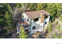 Charming two-story home featuring a spacious deck, surrounded by lush greenery and mature trees at 33090 Janelle Cir, Golden, CO 80403