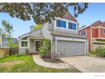 Charming two-story home with gray siding, a well-manicured lawn, and a two car garage at 744 Owl Dr, Louisville, CO 80027
