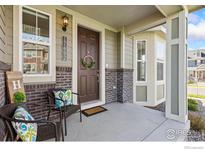 Inviting front porch with decorative wreath, brick accents, and comfortable seating at 17692 Olive St, Broomfield, CO 80023