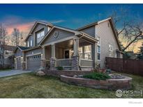 Charming two-story home featuring a covered front porch and attached two-car garage, stone veneer accents and landscaped front yard at 1831 Ashford Cir, Longmont, CO 80504