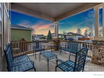 Inviting covered patio with stone accents and metal seating, perfect for outdoor relaxation and enjoying the sunset at 1831 Ashford Cir, Longmont, CO 80504