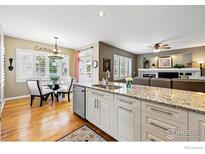 Open-concept kitchen with granite countertops, stainless steel appliances, and hardwood floors at 301 Widgeon Ln, Longmont, CO 80503