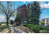 Brick building exterior with mature trees and landscaping near a sidewalk on a partly cloudy day at 4110 Hale Pkwy # 5F, Denver, CO 80220