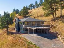 Contemporary two-story home with a spacious deck and inviting curb appeal, nestled into a hillside lot with mature trees at 6465 Red Hill Rd, Boulder, CO 80302