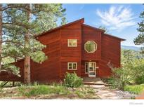 Striking two-story home with unique octagonal window and wood facade surrounded by mature trees at 1101 Peakview Cir, Boulder, CO 80302