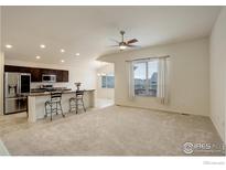 Inviting living room featuring plush carpeting, a ceiling fan, and a large window for ample natural light at 1540 Murrlet St, Berthoud, CO 80513