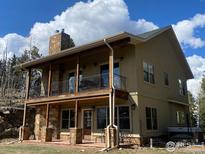 Stunning two-story home showcasing a stone chimney and balcony on a sunny day at 1555 Three Peaks Rd, Golden, CO 80403