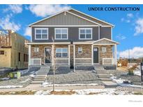New construction townhome featuring stone accents and covered entryways, providing curb appeal at 18714 E 99Th Ave, Commerce City, CO 80022