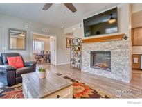 Inviting living room features a stone fireplace, wooden floors, and access to an office space at 2417 Calais Dr # 19 D, Longmont, CO 80504