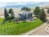 Stunning home featuring lush green lawn, mature trees, an outdoor patio set, and mountain views at 3159 Nelson Rd, Longmont, CO 80503
